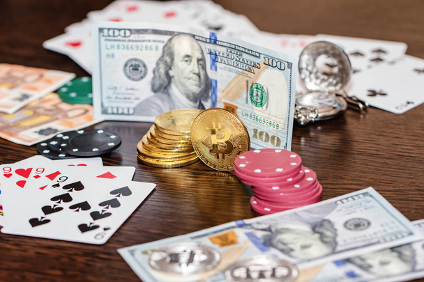 Атрибуты азартных игр на деревянном столе - деньги, карты, фишки и биткоины
 - Фото, изображение