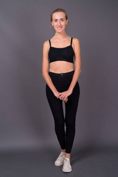 Young beautiful woman ready for gym against gray background - Photo, image