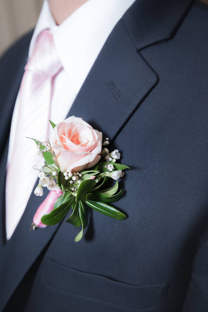 eine rosa Rose boutonniere auf einer marineblauen Jacke für Männer. - Foto, Bild