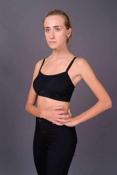 Young beautiful woman ready for gym against gray background - Фото, зображення