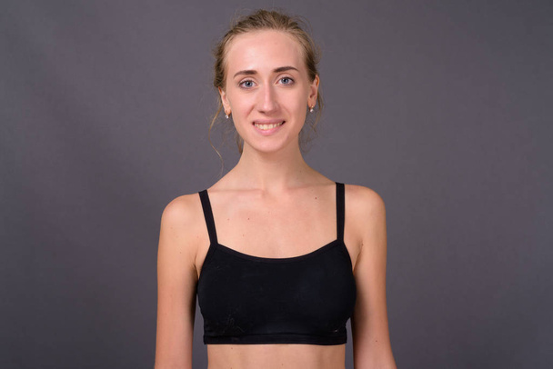 Young beautiful woman ready for gym against gray background - Fotoğraf, Görsel
