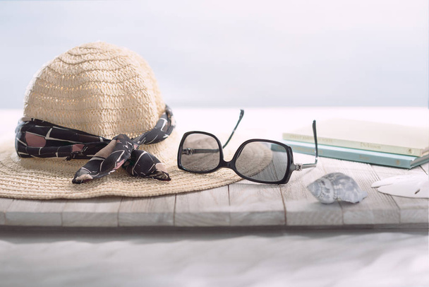 Scène de lecture à la plage avec chapeau et lunettes de soleil
. - Photo, image