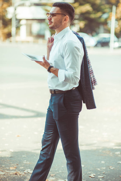 Kaukasischer Geschäftsmann im weißen Hemd mit Tablette an sonnigem Tag im Freien - Foto, Bild