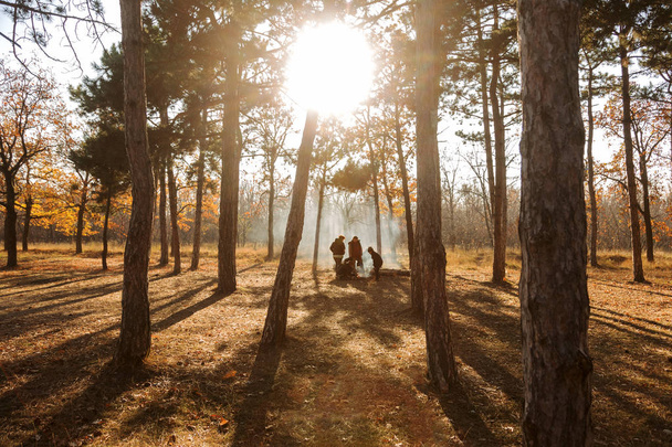 Odessa, Oekraïne Cirka 2018: Vreugdevuur in bos. Bedrijf, familie op picnic in herfst bos, ontsteekt een vuur van bijkantoren voor het koken van vlees. Gevaar van bosbranden in naaldhout droog bos. Brand in het bos - Foto, afbeelding