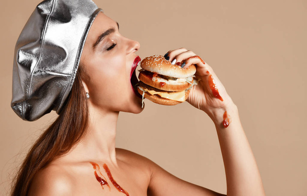 Woman hold burger sandwich  with ketchup with hungry mouth on light brown background - Foto, immagini