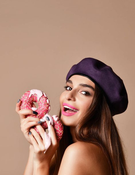 Woman hold Sweet pink sugar donuts hungry mouth on light brown background - Fotó, kép