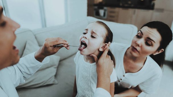 Doctor Visiting Little Girl in Red Scarf with Cold. Sick Young Girl. White Sofa in Room. Doctor in Uniform. Disease Concept. Healthcare and Healthy Lifestyle Concept. Mother with Daughter. - 写真・画像