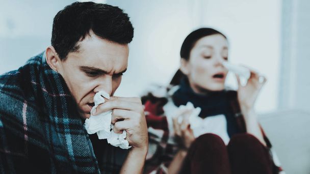 Sick Couple Sitting on Sofa in Checkered Blankets. Man at Home. Sick Young Woman. White Sofa in Room. Unhappy Guy. Disease Concept. Healthcare and Healthy Lifestyle Concept. Using Nasal Spray. - Φωτογραφία, εικόνα
