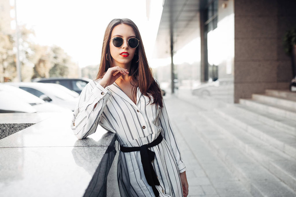 Summer sunny lifestyle fashion portrait of young stylish hipster woman with sunglasses walking on the street, wearing cute trendy outfit enjoy her weekends, travel alone - Φωτογραφία, εικόνα