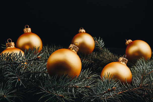 Christmas or New Year toy decorations golden ball and fur tree branch rustic on wooden background, top view, copy space - 写真・画像