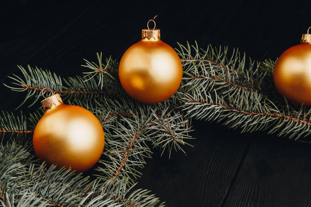 Christmas or New Year toy decorations golden ball and fur tree branch rustic on wooden background, top view, copy space - Fotó, kép
