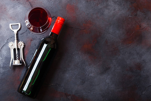 Elegant glass and bottle of red wine with corkscrew opener on kitchen table background. - Foto, afbeelding