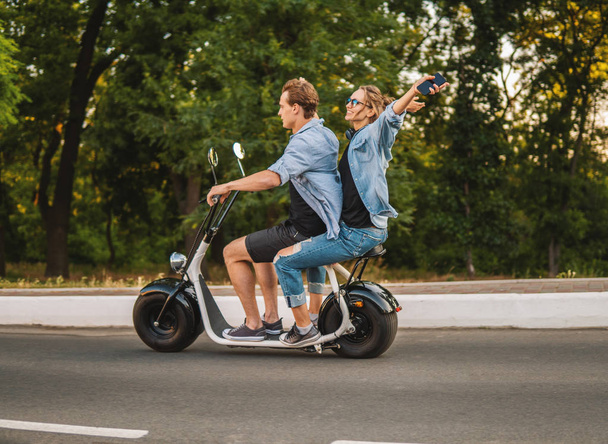 Lovely young couple driving electric bike during summer - Fotoğraf, Görsel