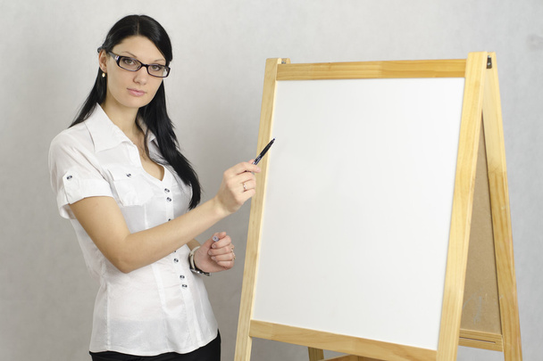 επιχείρηση κορίτσι με τα γυαλιά δείχνει ένα δείκτη σε έναν λευκό πίνακα - Φωτογραφία, εικόνα
