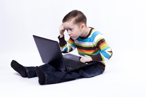 boy with a laptopBoy thinks looking at laptop - Fotoğraf, Görsel