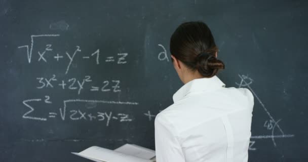 Portrait of a beautiful girl, teacher or student solves examples, formulas, triangle on a black board, on a black background. Concepts: ideas, algebra, mathematics geometry school university knowledge - Video