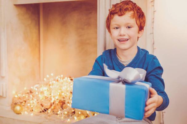 Pleasant ginger-haired giving Christmas present - Foto, afbeelding
