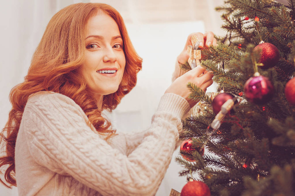 Beautiful red-haired woman festooning Christmas tree - Valokuva, kuva
