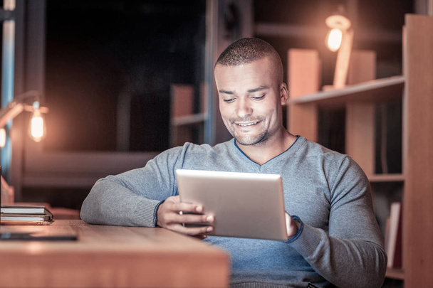 Positive delighted dark-skinned man using tablet - Photo, Image