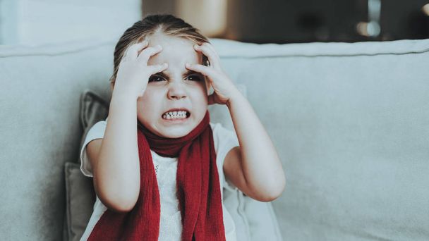 Little Girl with Cold Sitting on Sofa in Red Scarf. Sick Young Girl. White Sofa in Room. Unhappy Child. Disease Concept. Healthcare and Healthy Lifestyle Concept. Little Girl at Home. - Fotoğraf, Görsel