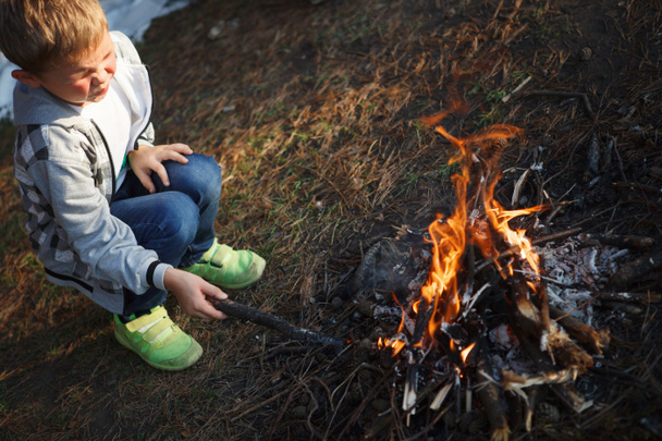 Junge im karierten Hemd macht Feuer im herbstlichen Wald. - Foto, Bild
