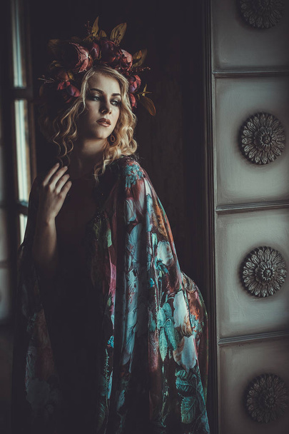 Beautiful woman in a dress of floral colors stands in the palace - Фото, зображення