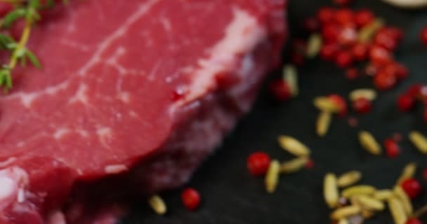 Beautiful juicy fresh meat steak on a table with salt, rosemary, garlic, and tomato on a black background, top view. Concept: fresh & natural products, bio products, meat products, organic, nutrition. - Filmmaterial, Video