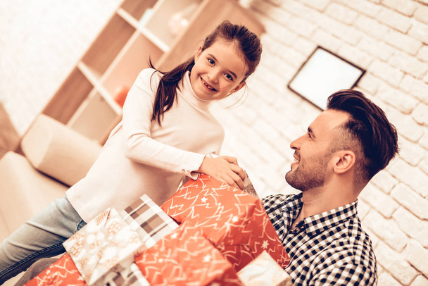Father and Daughter on Sofa. Spend Time Together. Father's day. Man Play with Girl. Smiling Girl at Home. Sit on Sofa. Gift box. Gift in Red Pack. Man with Gift for Child. Make Surprise for Daughter. - Foto, Bild