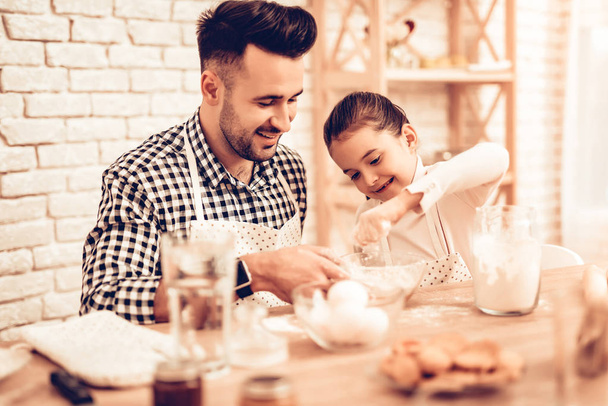 Cook Food at Home. Happy Family. Father's Day. Girl and Man Cooking. Smiling Man and Child at Table. Spend Time Together. Food on Table. Break Egg in Bowl. Pour Flour. Cook Dough. Pour Flour in Bowl. - Φωτογραφία, εικόνα