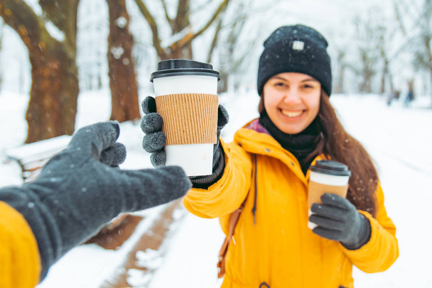 woman give cup of coffee to friend. meeting in snowed winter park concept - 写真・画像
