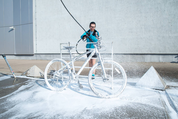 Νέος αθλητισμός γυναίκα πλύσιμο ποδηλάτων στο self service αυτοκίνητο πλύσιμο - Φωτογραφία, εικόνα
