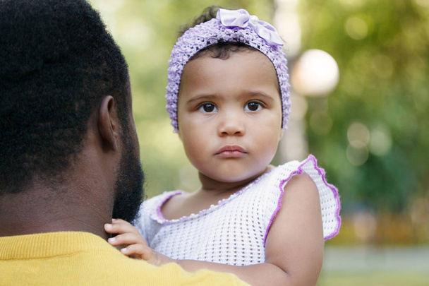 Αφρικανική αμερικανική πατέρας κρατά μια χαριτωμένη μικρή κόρη. - Φωτογραφία, εικόνα