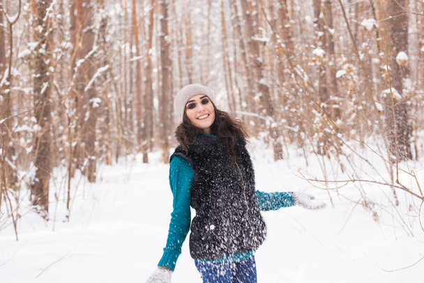 Saison, loisirs et concept de personnes - la jeune femme est heureuse et jette de la neige dans la nature hivernale
 - Photo, image