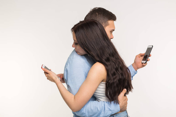 Smartphone addiction concept - Young couple using internet on mobile phone, ignoring each other. They are bored and sad - Foto, Imagen