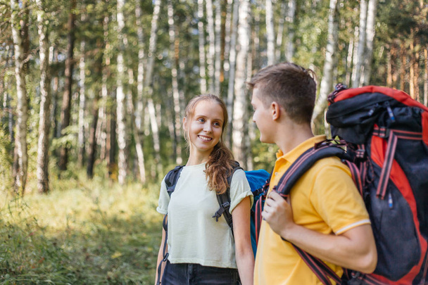 couple of tourists with backpacks hiking in a forest - Foto, Imagem