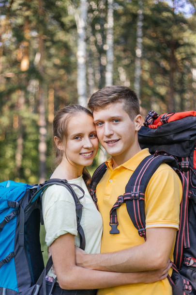 couple of tourists with backpacks hiking in a forest - Fotoğraf, Görsel