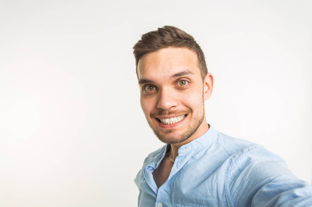 ファッションと人のコンセプト - ハンサムな男を作る selfie 写真と白い背景の笑顔 - 写真・画像