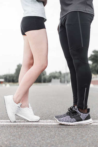 Love sport concept - running couple kissing. Closeup of running shoes and girl standing on toes to kiss boyfriend during jogging workout training outdoors - Foto, afbeelding