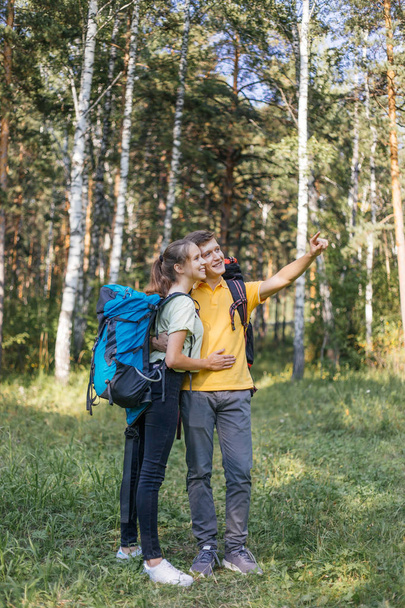 couple of tourists with backpacks hiking in a forest - Foto, Imagen