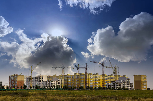 Место строительства нового многоэтажного дома с башенными кранами на фоне голубого неба. Развитие жилых районов. Концепция роста проекта недвижимости
. - Фото, изображение