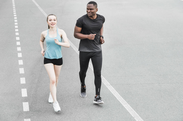 happy young couple afro-american man and european woman running together. A loving couple is run, engaged in sports, family values - Foto, imagen