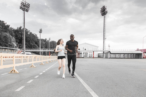 happy young couple afro-american man and european woman running together. A loving couple is run, engaged in sports, family values - Fotografie, Obrázek