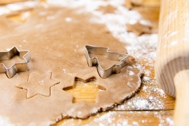 Різдвяне імбирне печиво: пряникове тісто, форми випічки та кухонне начиння на дерев'яному столі
 - Фото, зображення