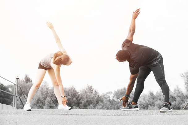 a pair of athletes do a warm-up. A loving couple an African American man and a European woman are sporting - Foto, imagen
