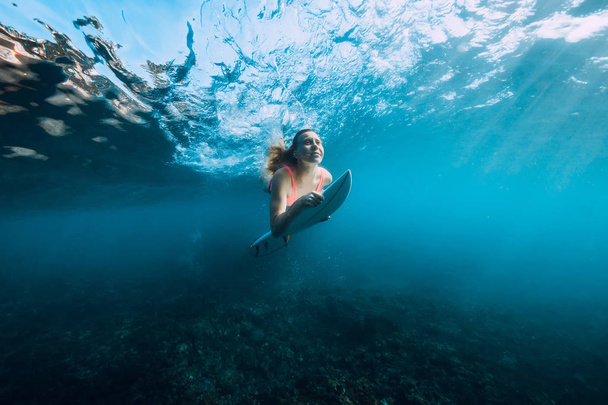 Femme surfeuse en bikini avec planche de surf plongée sous tonneau océan vague
 - Photo, image