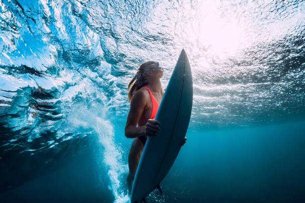 surfer γυναίκα κατάδυση κάτω από το κύμα στον ωκεανό - Φωτογραφία, εικόνα