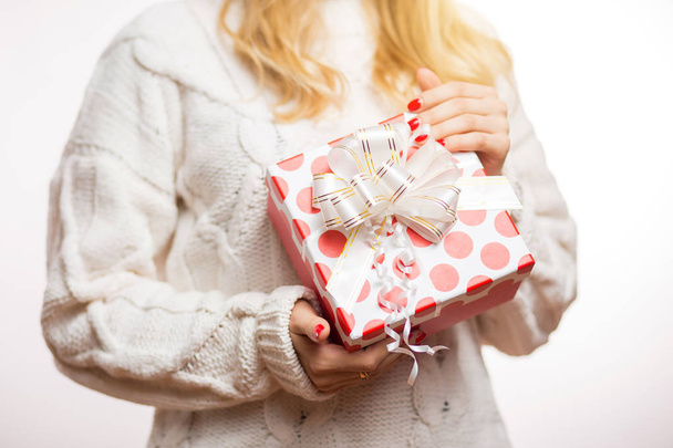 Beautiful red box with a gift on the hand of a blonde woman on a white background. Christmas, new year, birthday and celebration concept - Foto, Imagem