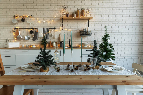 Nieuwjaar en Kerstmis 2018. Feestelijke keuken in kerstversiering. Kaarsen, vuren takken, houten tribunes, tafel leggen. - Foto, afbeelding