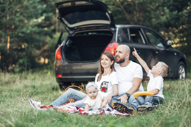 Młoda para z ich małymi dziećmi, piknik w lesie, koncepcja rodzinny Weekend, czterech osób korzystających lato - Zdjęcie, obraz