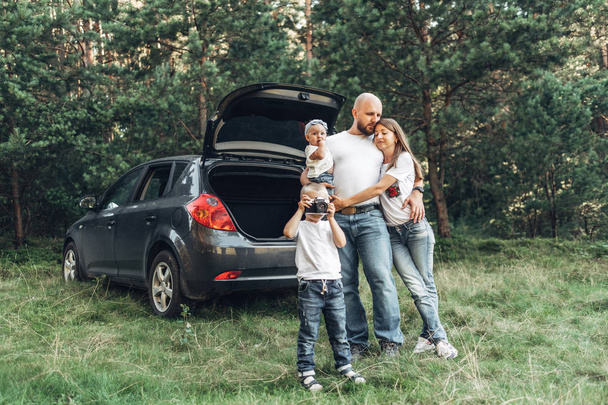 Jong koppel dat met hun kleine kinderen hebben Picnic in bos, familieweekend Concept, vier mensen genieten van de zomer - Foto, afbeelding